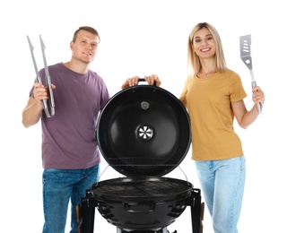 Photo of Happy couple with barbecue grill and utensils on white background