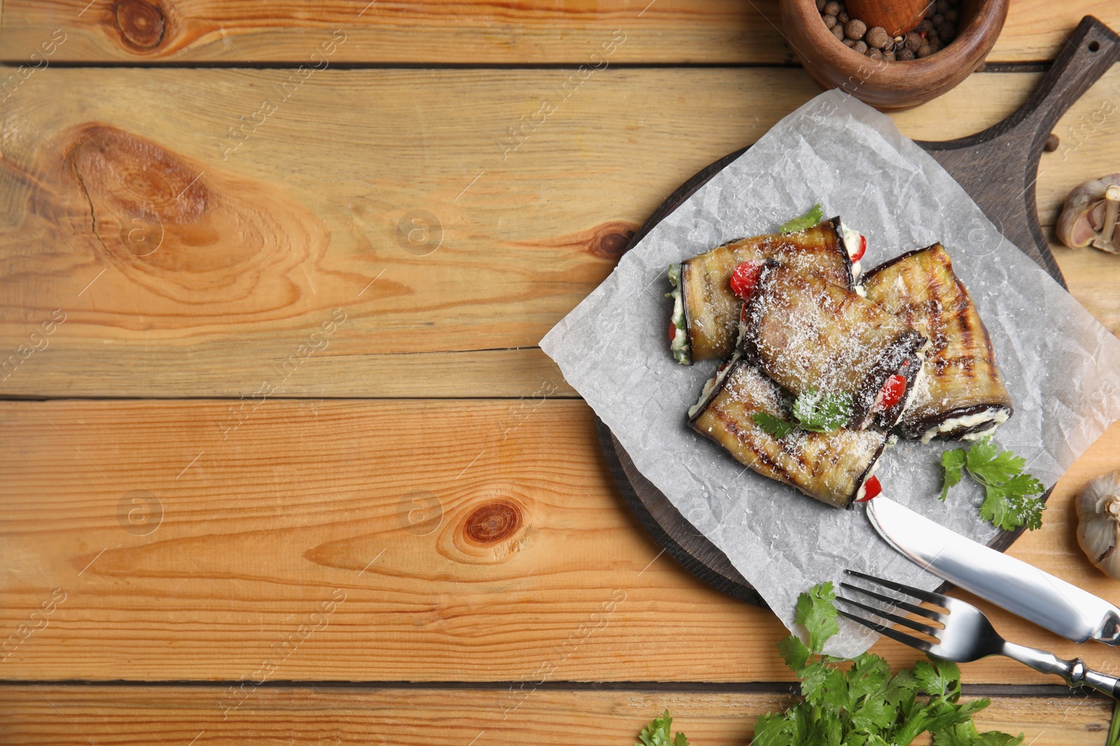 Photo of Delicious baked eggplant rolls served on wooden table, flat lay. Space for text