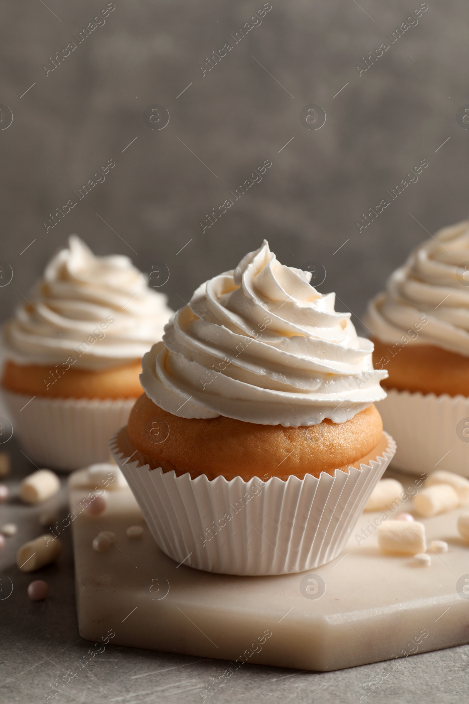 Photo of Delicious cupcakes decorated with cream on light grey table