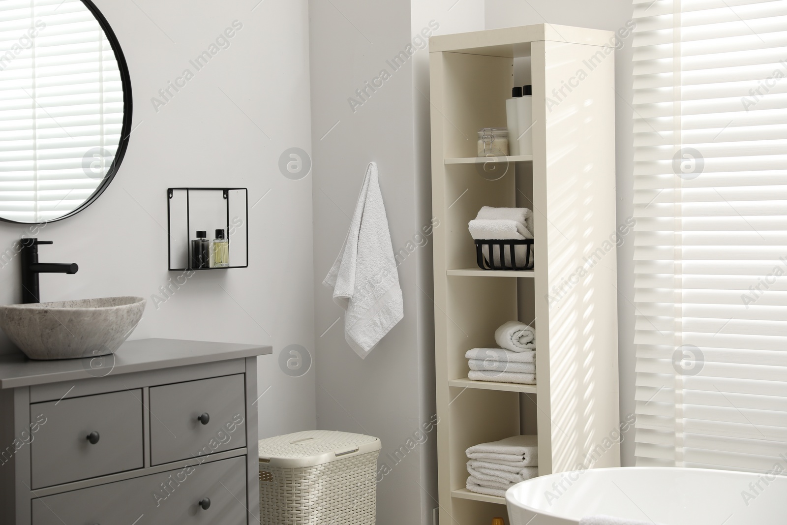 Photo of Stylish bathroom interior with grey chest of drawers and shelving unit