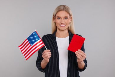 Immigration. Happy woman with passport and American flag on gray background