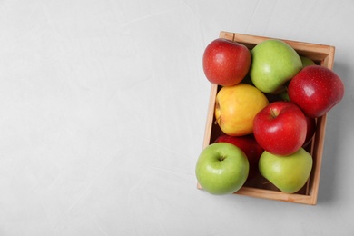 Photo of Wooden crate filled with fresh juicy apples on table, top view. Space for text