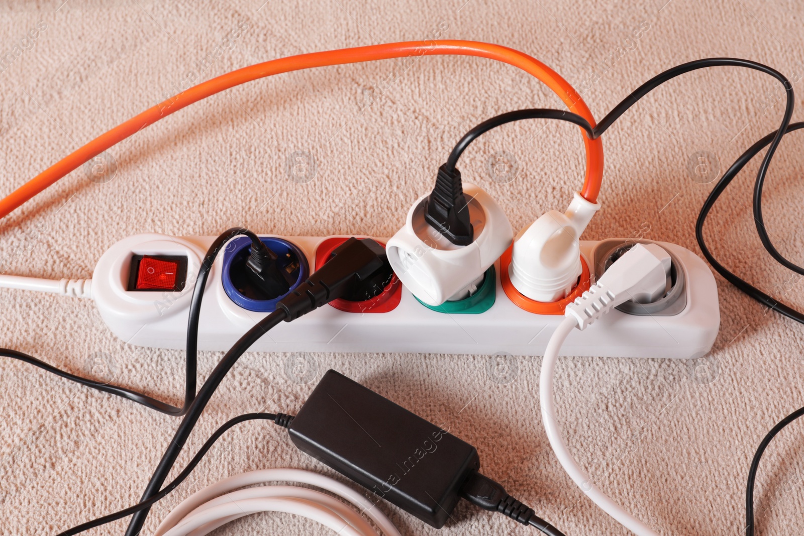 Photo of Power strip with different electrical plugs on white carpet