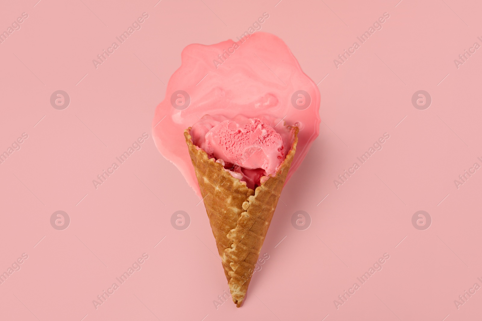 Photo of Melted ice cream in wafer cone on pink background, top view