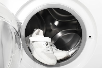 Photo of Stylish clean sneakers inside modern washing machine