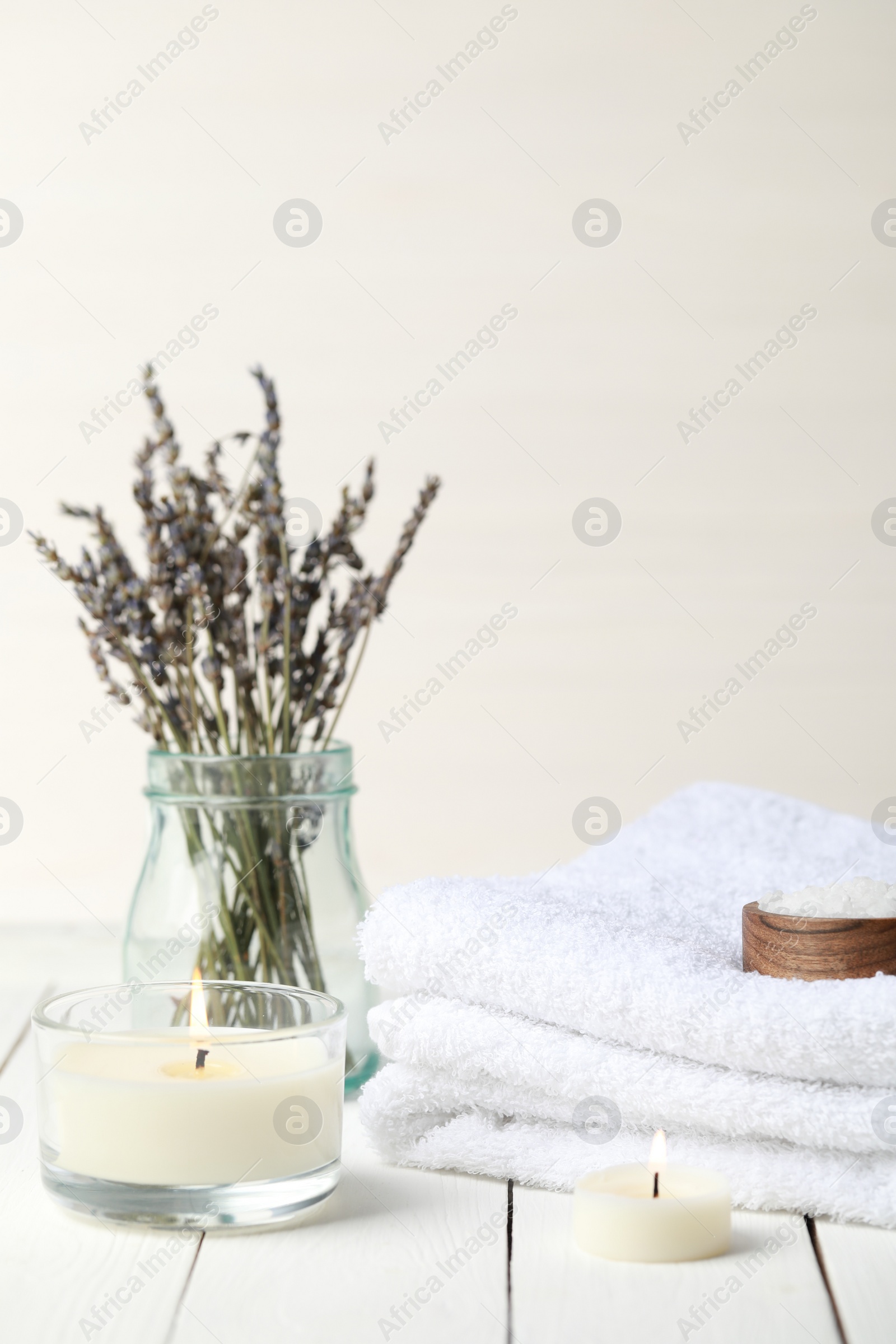 Photo of Beautiful composition with burning candles and different spa products on white wooden table