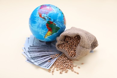 Photo of Import and export concept. Globe, bag of wheat grains and banknotes on beige background