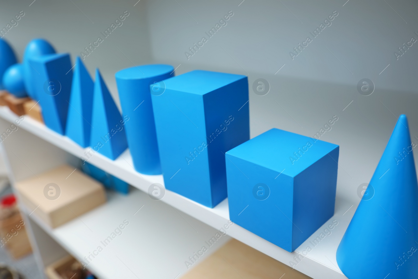 Photo of Set of wooden geometrical objects and other montessori toys on shelves