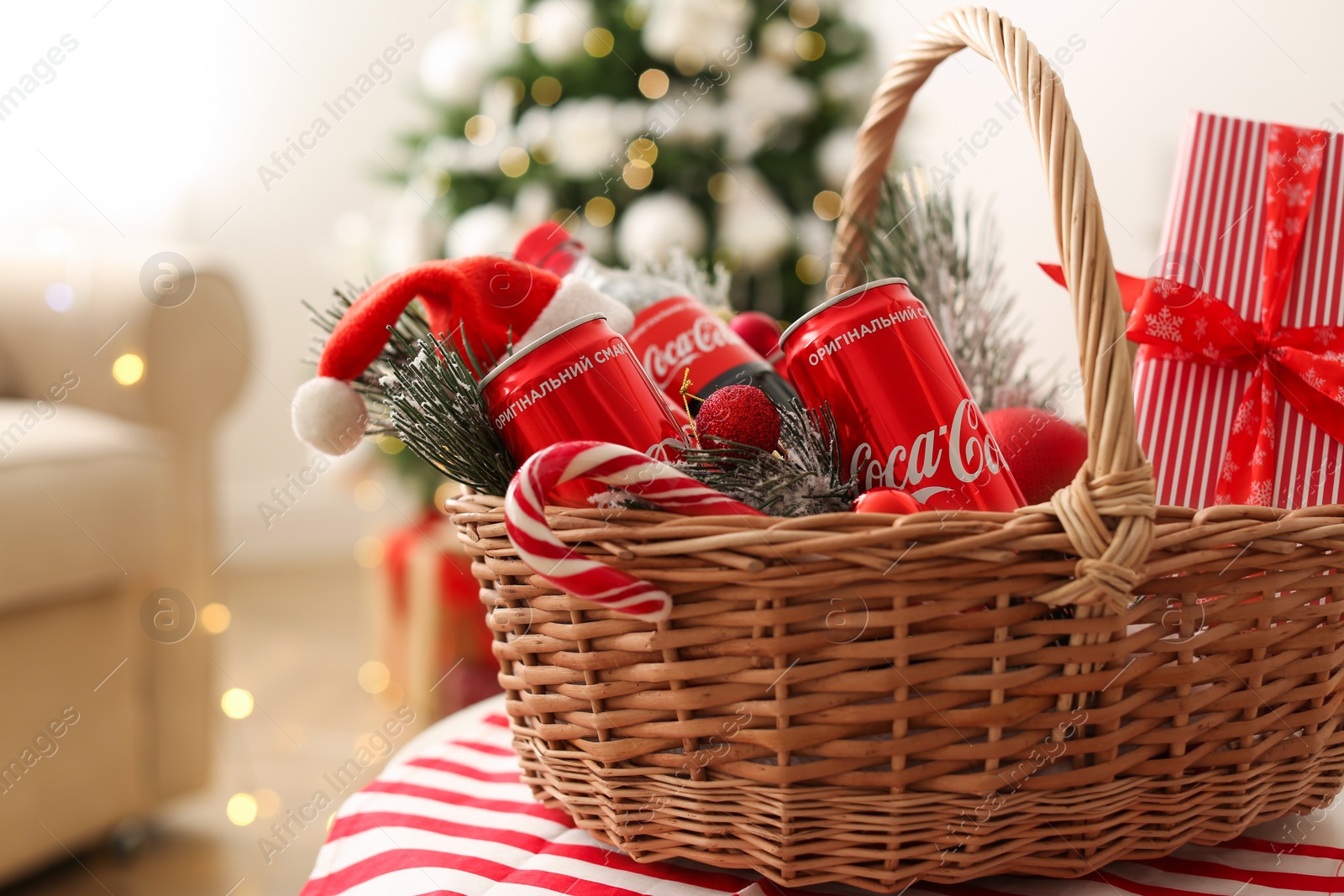 Photo of MYKOLAIV, UKRAINE - January 01, 2021: Basket with Coca-Cola drinks against blurred Christmas tree