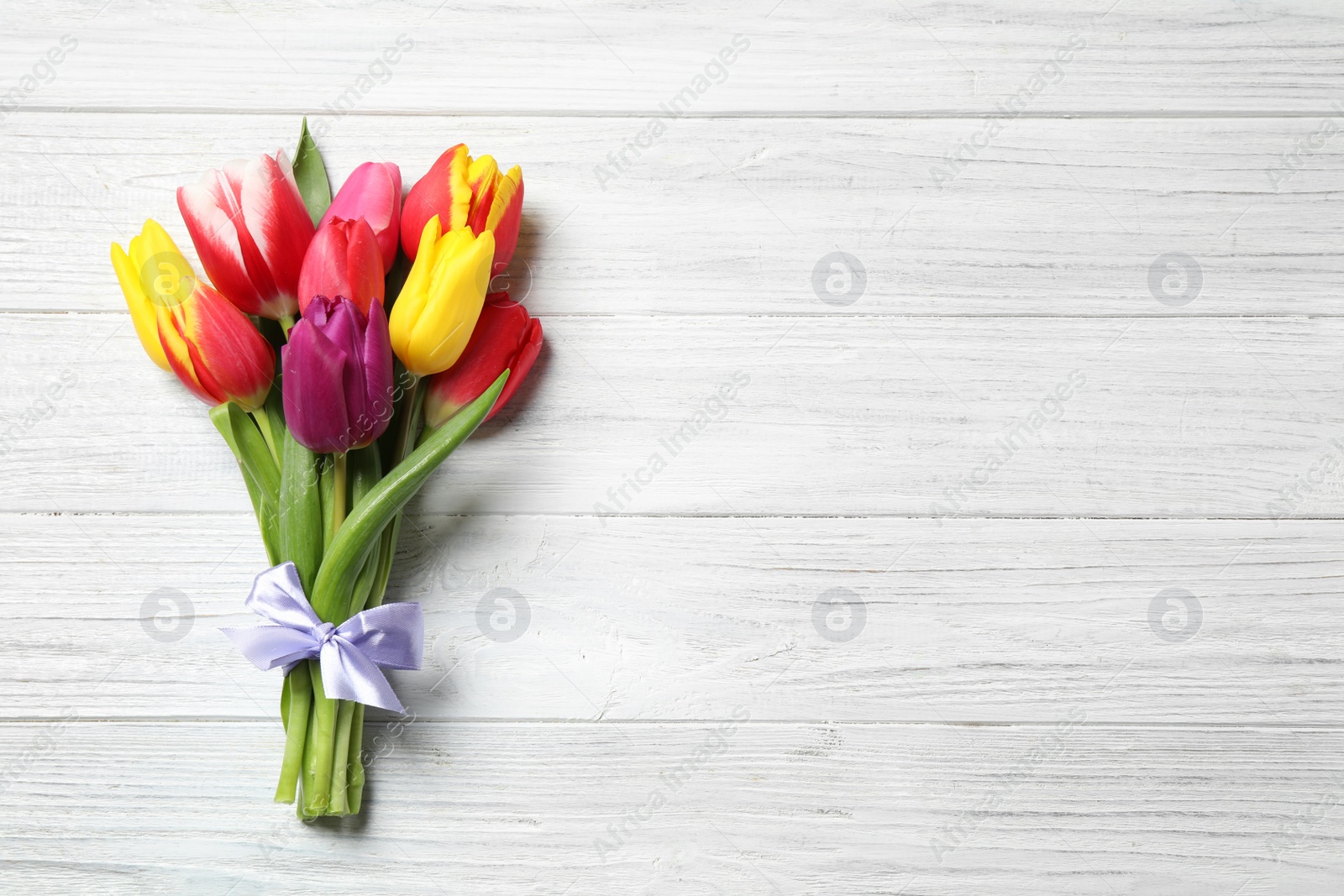 Photo of Beautiful spring tulips on white wooden table, top view. Space for text