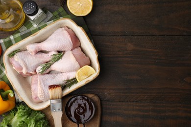 Flat lay composition with marinade and raw chicken drumsticks on wooden table. Space for text