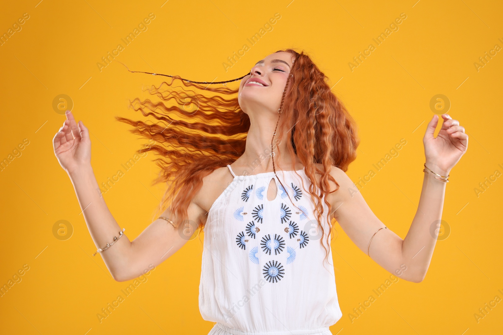 Photo of Beautiful young hippie woman dancing on orange background