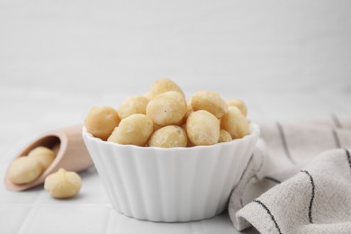 Photo of Bowl and scoop with peeled Macadamia nuts on white table