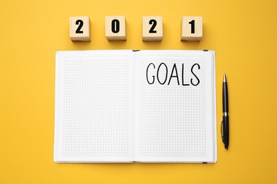 Photo of Flat lay composition with notebook on yellow background. Goals for New Year 2021
