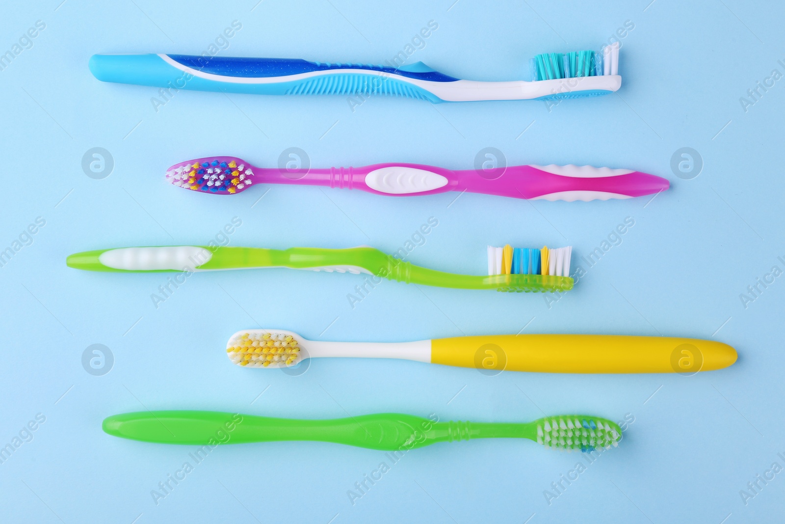 Photo of Many different toothbrushes on light blue background, flat lay