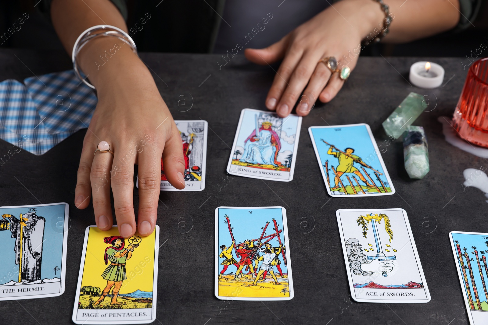 Photo of Fortune teller predicting future on spread of tarot cards at grey table, closeup