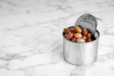 Photo of Tin can with kidney beans on white marble table, space for text