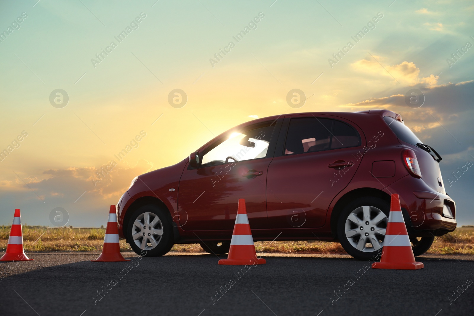 Photo of Traffic cones near red car outdoors. Driving school exam