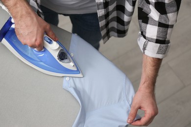 Photo of Man ironing clean shirt at home, above view