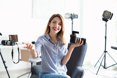 Portrait of female photo blogger with camera at home