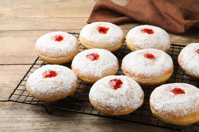 Many delicious donuts with jelly and powdered sugar on wooden table