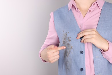 Photo of Woman showing stain from sauce on her shirt against light grey background, closeup. Space for text