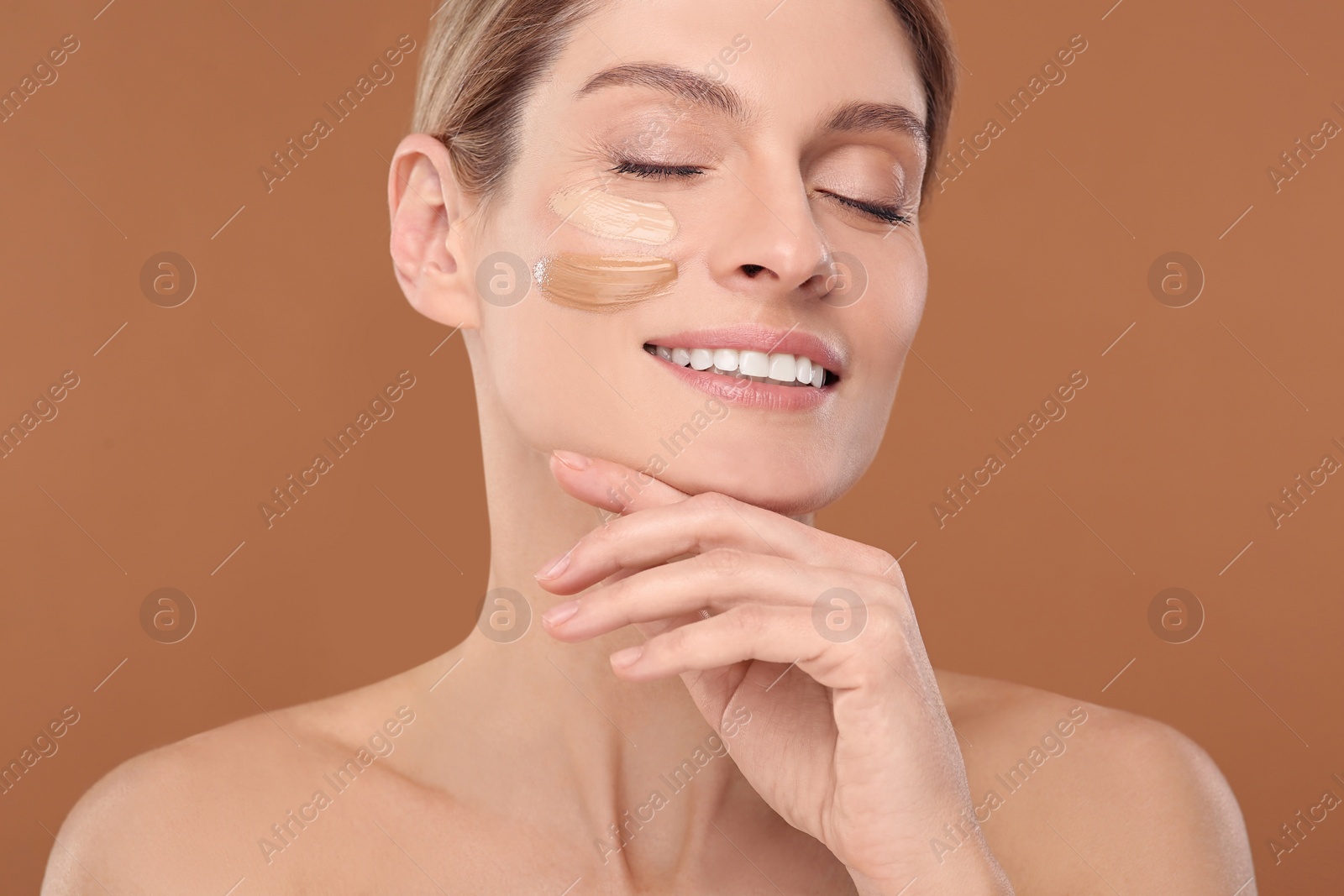 Photo of Woman with swatches of foundation on face against brown background