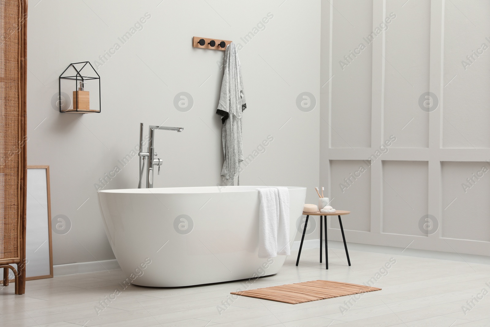 Photo of Modern ceramic bathtub with towel near white wall in room