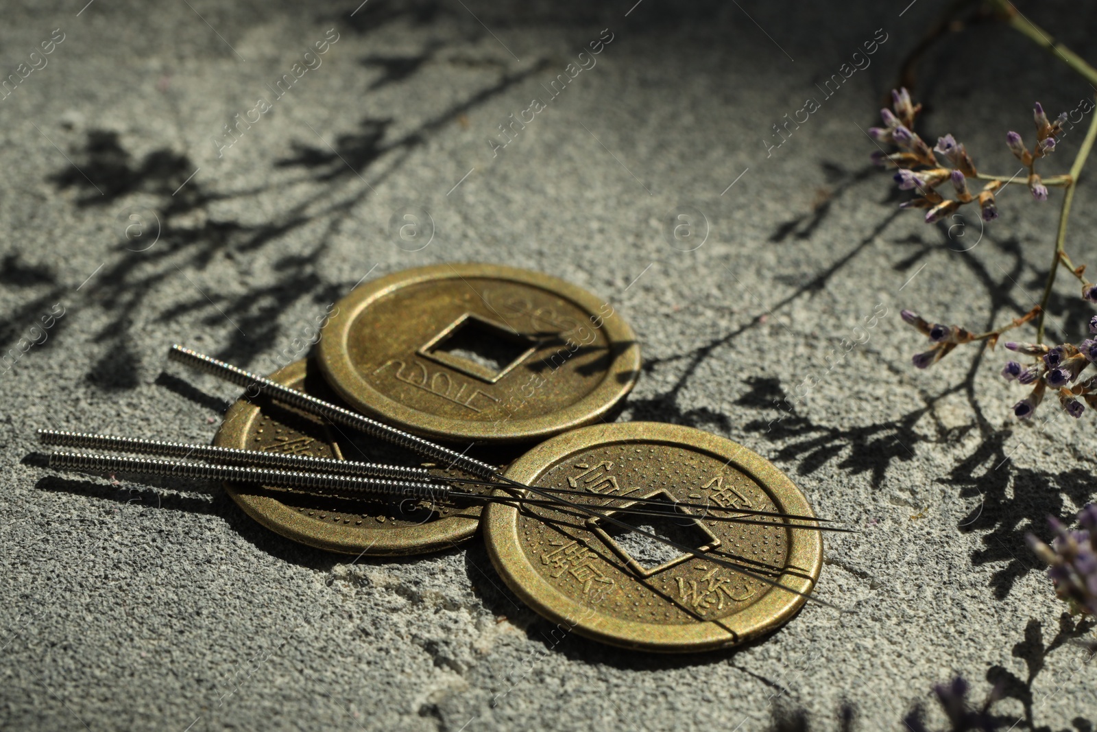 Photo of Acupuncture needles and Chinese coins on stone surface