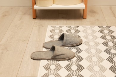 Photo of Stylish bath mat with soft slippers on floor indoors