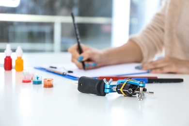 Photo of Professional tattoo machine and blurred master on background