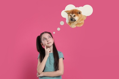 Little girl dreaming about cute puppy, pink background