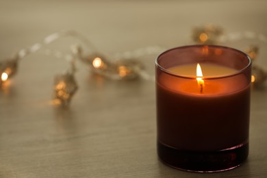 Burning candle in holder on table, closeup. Space for text