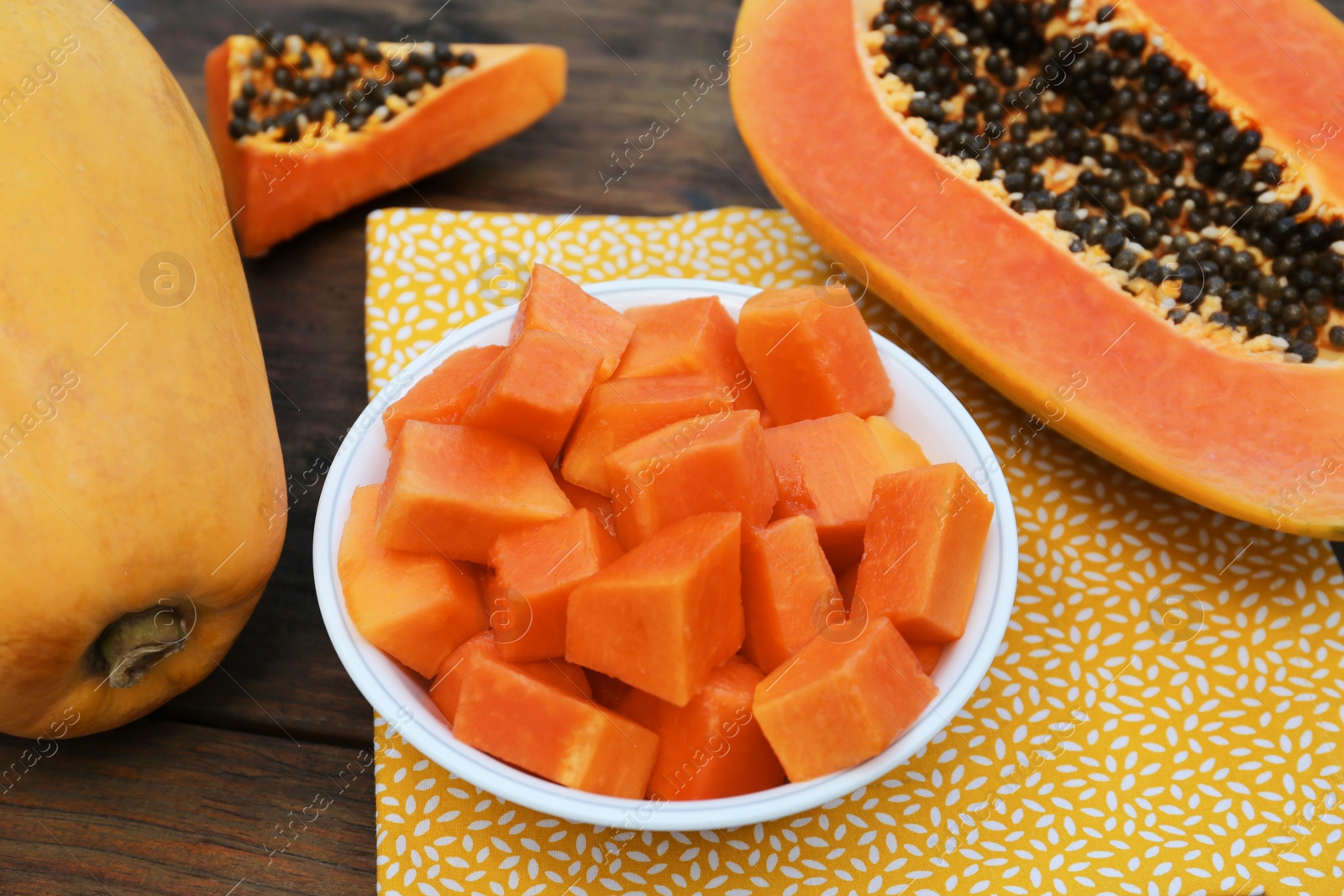 Photo of Tasty whole and cut papaya fruits on wooden table, closeup