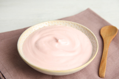 Photo of Tasty organic yogurt and spoon on fabric