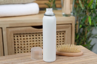 Dry shampoo spray and hairbrush on wooden table in bathroom