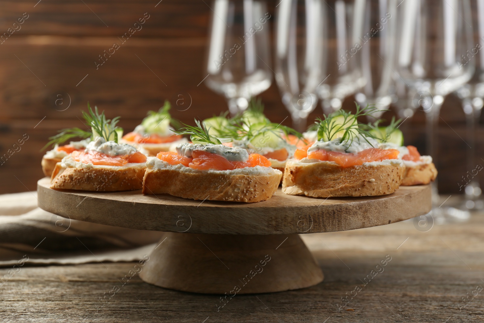 Photo of Tasty canapes with salmon, cucumber, cream cheese and dill on wooden table