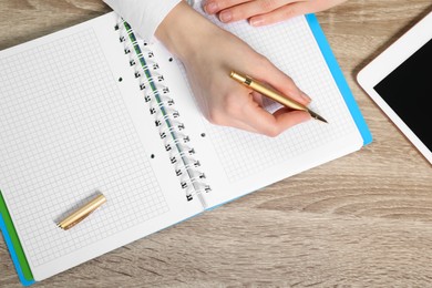 Photo of Woman taking notes at wooden table, top view