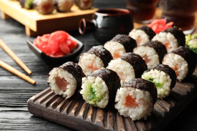 Tasty sushi rolls served on black wooden table