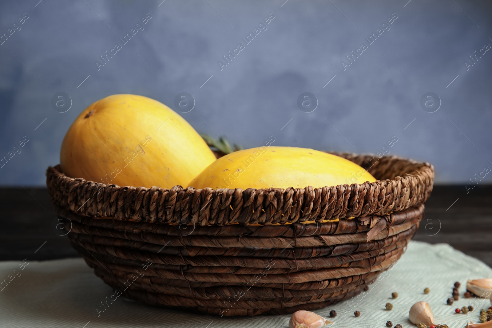 Photo of Basket with ripe spaghetti squashes on table against color background