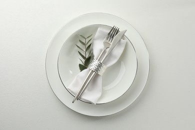 Photo of Stylish setting with cutlery and napkin on white textured table, top view