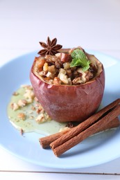 Photo of Tasty baked apple with nuts, honey, spices and mint on white wooden table, closeup