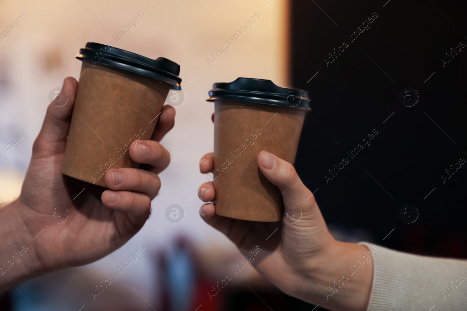 Photo of Couple with takeaway coffee cups in cafe, closeup