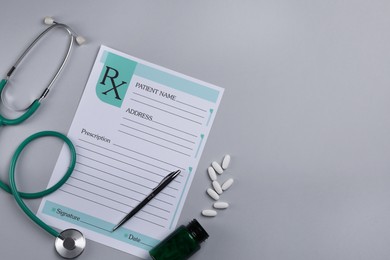 Photo of Medical prescription form, stethoscope, pills and pen on light grey background, flat lay. Space for text