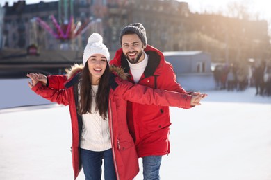 Image of Lovely couple spending time together at outdoor ice skating rink