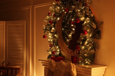 Photo of Mirror with Christmas garland and fairy lights over fireplace in room