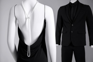 Photo of Male and female mannequins dressed in elegant outfits on grey background, selective focus