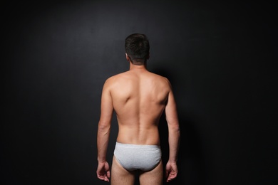 Young man wearing underwear on black background