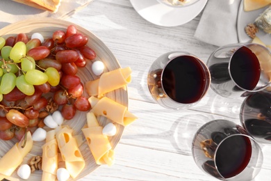 Composition with red wine and snacks on white wooden table, above view