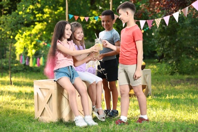 Photo of Cute little children with natural lemonade in park. Summer refreshing drink